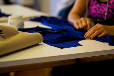 Midsection of woman sewing fabric on table