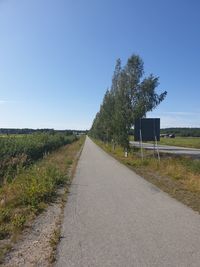 Empty road amidst field against clear sky