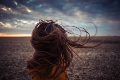 Girl with tousled hair at beach during sunset