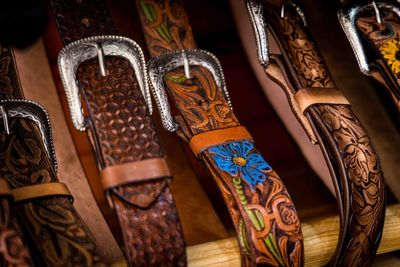 Cowboy boots and leather belts in a saddlery, footwear and accessories business showcase.