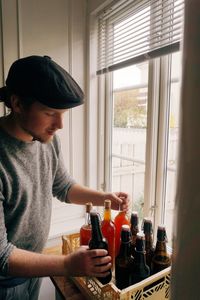 Man holding bottles while standing by window at home