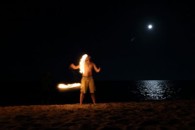 Rear view of man standing on beach at night