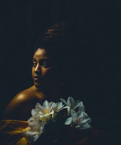 Portrait of woman with white flowers against black background