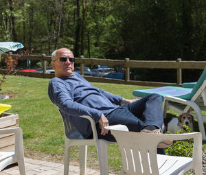 Mature man relaxing on chair in yard during sunny day