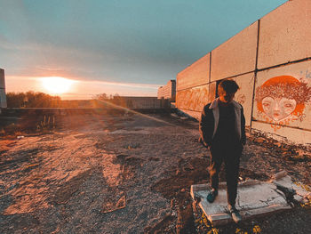 Rear view of man standing against sky during sunset