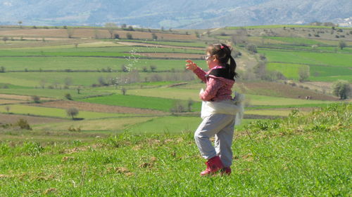 Side view of girl standing on grassy field