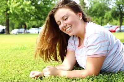 Cheerful young woman lying at park