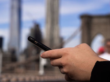 Midsection of person holding cigarette against sky