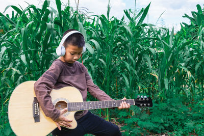 Full length of man playing guitar against plants