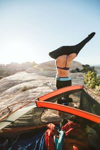 Woman changes clothes as the sun sets over her campsite