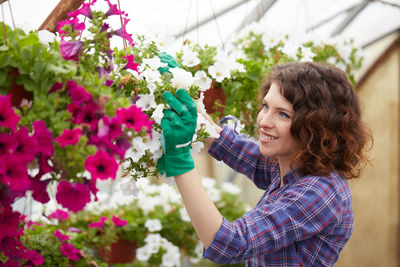 Smiling woman holding flowers in greenhouse