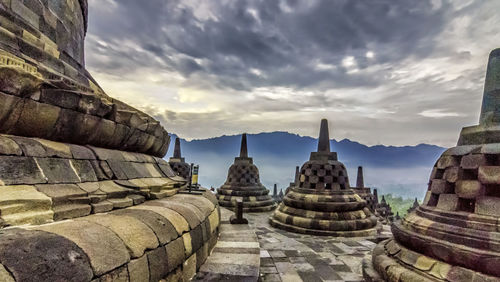 Stupas at borobudur temple against cloudy sky