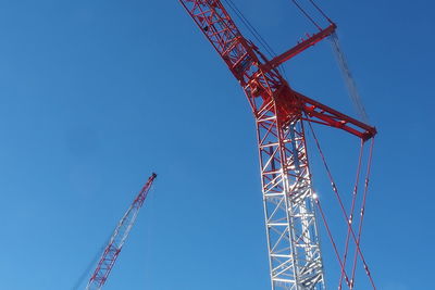 Low angle view of crane against clear blue sky