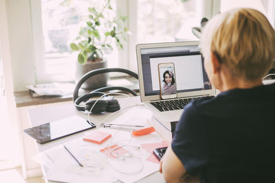 Rear view of man using laptop on table