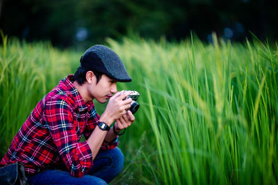 Young woman using mobile phone while sitting on land