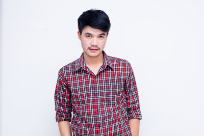 Portrait of young man standing against white background