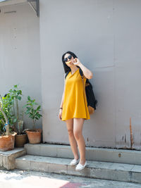 Full length of woman standing against yellow wall