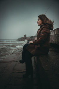 Side view of young woman sitting on beach