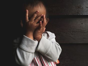 Portrait of a boy covering face with hand