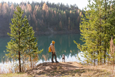 Rear view of man standing on rock by lake