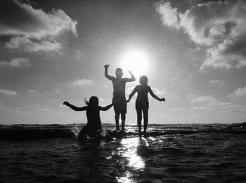 Friends enjoying at beach against sky