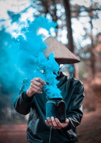 Man holding jar with blue smoke forming by chemical reaction