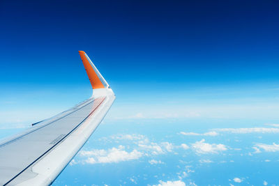 Aerial view of aircraft wing against blue sky