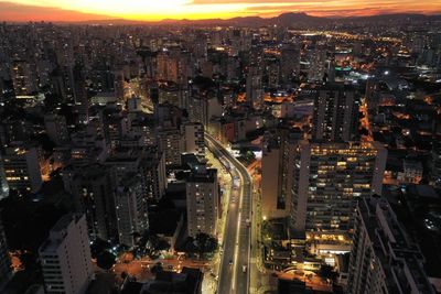 High angle view of illuminated street amidst buildings in city at night