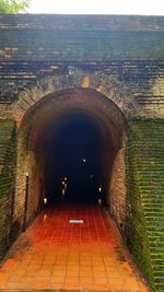 Empty illuminated tunnel amidst buildings in city