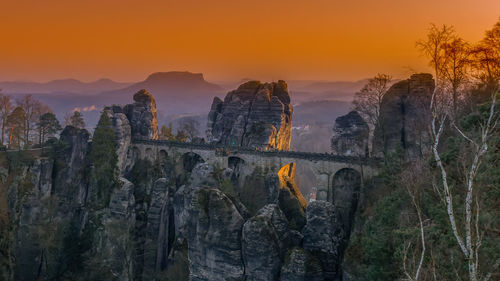 Panoramic shot of bridge over sea against orange sky