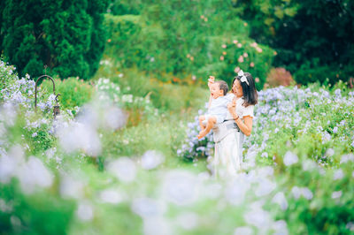 Mother and son standing by plants outdoors