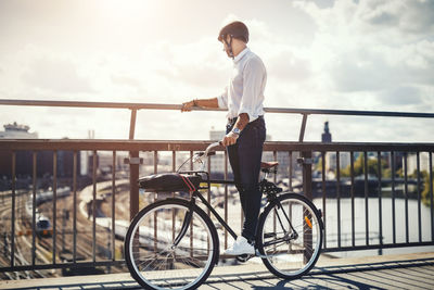 Businessman looking at city view while standing on bicycle
