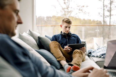 Teenage boy using digital tablet on sofa at home