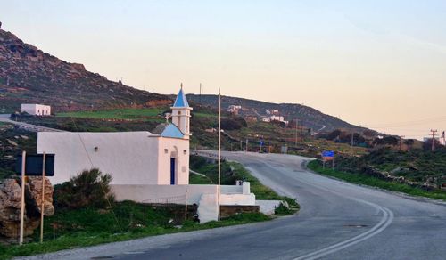 Road by buildings in town against clear sky