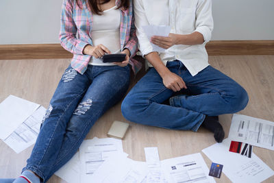 High angle view of friends sitting on wooden floor