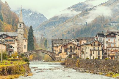 Arch bridge over river amidst buildings in city