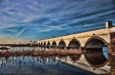 Arch bridge over river against sky