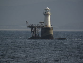 Lighthouse by sea against sky