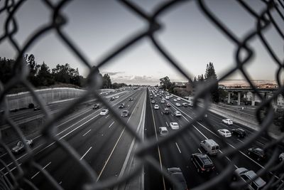 Close-up of chainlink fence against sky in city