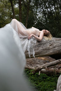 Woman lying on log in forest