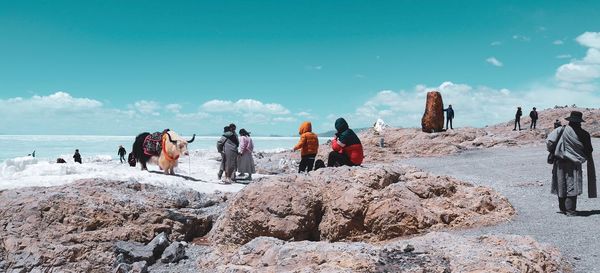 People standing on rock by frozen lake 