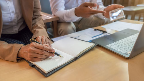 Midsection of man using mobile phone while sitting on table