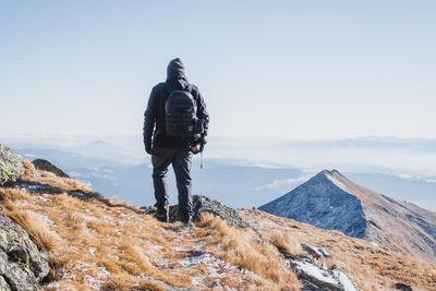 Rear view of man standing on mountain against sky