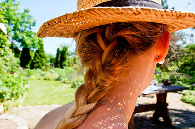 Rear view of woman with braided hair wearing sun hat in yard