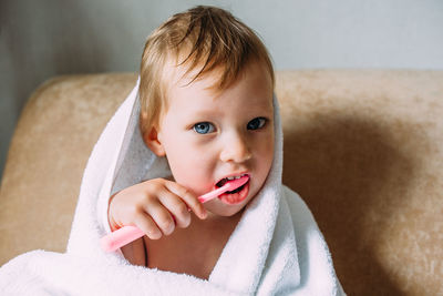 Cute child in big white towel. she brushes his teeth with toothbrush.