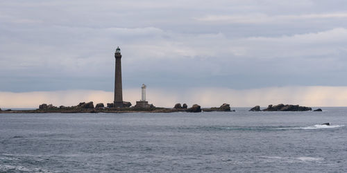 Lighthouse by sea against sky