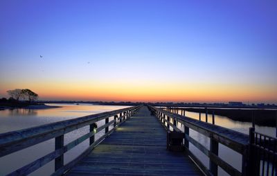 Pier over sea against clear sky during sunset