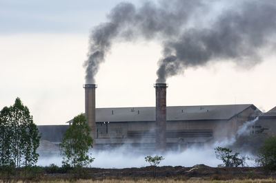 Smoke emitting from chimney against sky