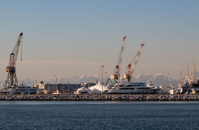 Cranes at commercial dock against sky