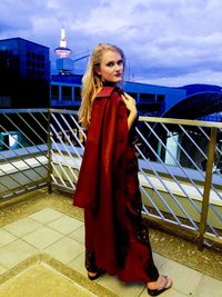 Portrait of woman standing by railing against sky